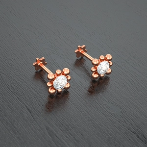 Macro detail of rose gold stud earrings featuring clear round crystals and beaded settings