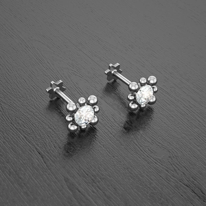 Macro detail of silver flower stud earrings with a brilliant-cut center gemstone