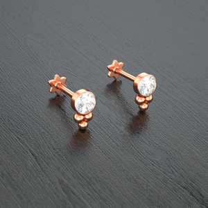 Macro shot of rose gold piercing studs with round crystals and star-shaped flat backs