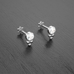 Macro detail of silver cartilage studs featuring crystal stone and star shaped back base