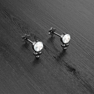 Detailed close-up of black metal studs with round zircon and star flat back base