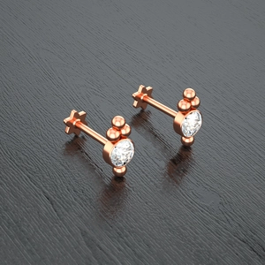Detail of rose gold piercing stud with round cubic zirconia and small metal spheres