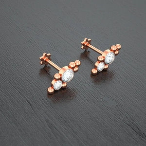 Detailed macro view of rose gold flat back piercing with triple crystal stone gradient