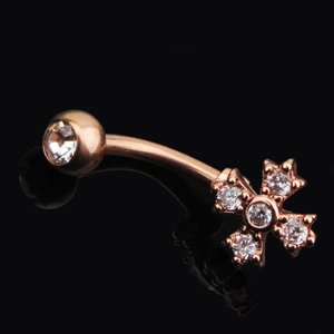 Makroaufnahme eines roségoldenen Bauchnabelpiercings mit Zirkonia-Kreuz und Spiegelung