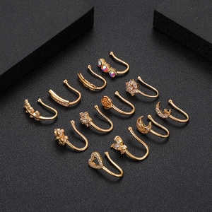 Détail de 11 faux anneaux de nez dorés avec incrustations de zircon sur fond noir