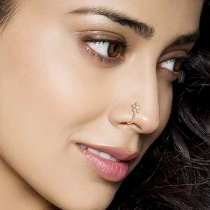 Macro shot of a gold floral nose ring featuring sparkling clear crystal petals on a model