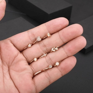 Dettaglio del set di piercing al naso in oro rosa con disegni a stella, cuore e zircone