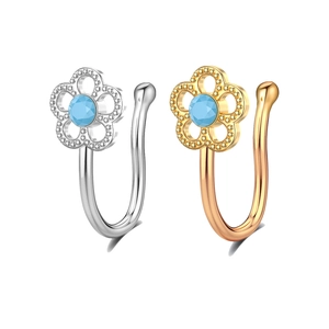 Macro detail of silver and gold non-piercing flower nose clips with blue gemstones