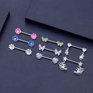 Set of zircon nipple rings with daisy butterfly and astronaut charms on black background