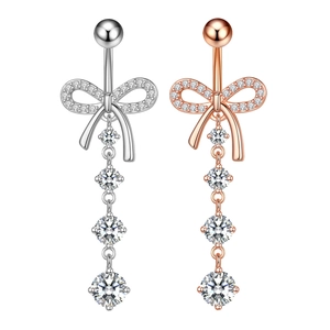 Detail of bow-shaped navel rings with cubic zirconia tassels in silver and rose gold
