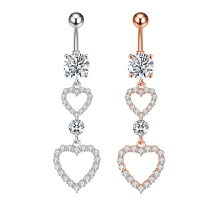 Detail of silver and rose gold belly button rings featuring layered heart zircon pendants
