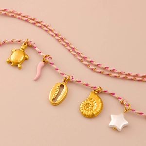Detalle de collar de cuerda tejida con colgantes de tortuga dorada, conchas y estrella