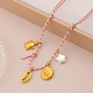 Detalle del collar tejido de verano con dijes dorados de tortuga, concha y estrella