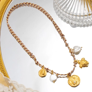 Detalle de collar bohemio con colgantes de tortuga dorada, perlas y acabado de lujo