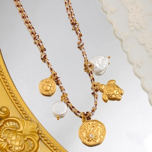 Foto macro de un collar de cordón trenzado vintage con colgantes dorados y perlas