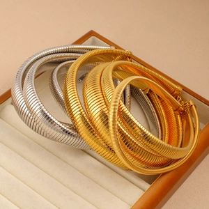 Détail macro de colliers oméga texturés en or et argent dans un coffret à bijoux de luxe