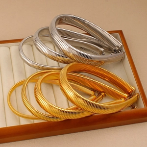 Close-up of gold and silver snake bone choker necklaces on a white velvet jewelry tray