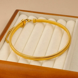 Détail d'une chaîne plate dorée avec fermoir mousqueton et extension dans un écrin à bijoux