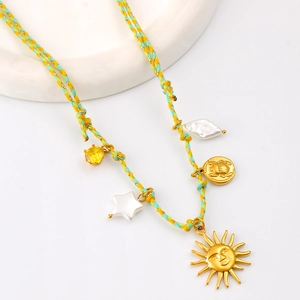 Détail du collier en corde tressée avec breloques soleil doré et étoile sur support blanc