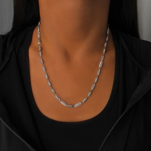 Détail du collier chaîne en acier inoxydable argenté avec maillons texturés sur sweat noir