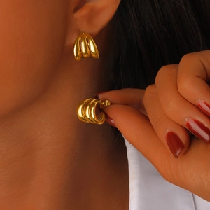 Détail de boucles d'oreilles dorées en forme de C avec texture festonnée à trois rainures