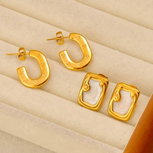 Détail de boucles d'oreilles dorées en U étoilées et clous en émail blanc vintage