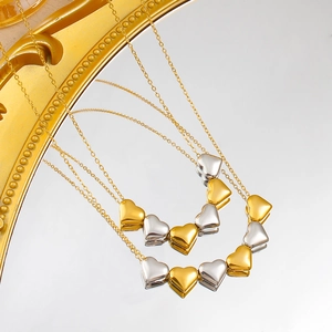 Zweifarbige Herz-Halskette in Gold und Silber auf einer edlen goldenen Spiegelfläche