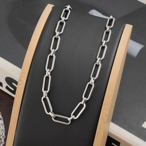 Détail du collier chaîne à maillons trombone en acier titane sur support de luxe