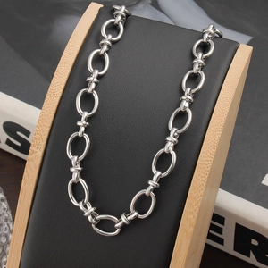 Gros plan d'un collier chaîne à maillons ovales en acier inoxydable poli sur support