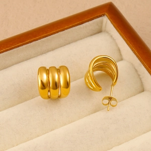 Vue détaillée des boucles d'oreilles créoles C en or 18K sur un coffret à bijoux en velours