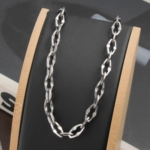 Détail d'un collier chaîne géométrique en acier inoxydable sur présentoir en cuir noir