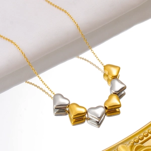 Detailaufnahme von 18K Gold- und Silber-Herzanhängern an einer schicken Halskette