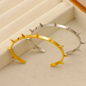 Dettaglio dei bracciali aperti in acciaio inossidabile oro e argento con borchie punk