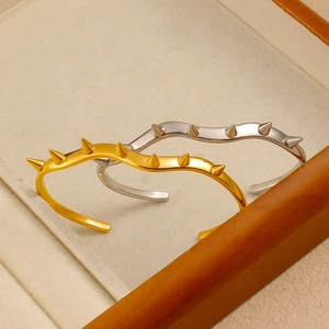 Dettaglio di bracciali ondulati in oro e argento con borchie coniche in stile punk