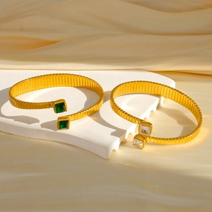 Dettaglio di bracciali elastici in acciaio placcato oro 18k con zirconi smeraldo e chiari