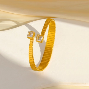 Dettaglio di un bracciale in acciaio dorato 18k con zirconi quadrati e design a maglie di catena