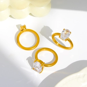 Detail of gold wide band ring featuring a large oval cubic zirconia in four-prong setting