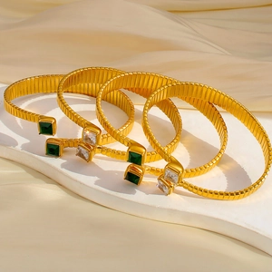Dettaglio macro di bracciali flessibili placcati oro 18K con zirconi quadrati lucidi