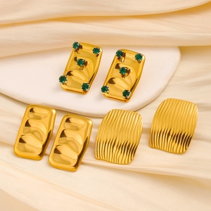 Vintage gouden oorbellen set met groene zirkoonstenen op een luxe displaystandaard