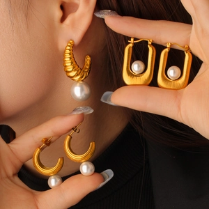 Vue détaillée de boucles d'oreilles perles luxe en forme de C dorées 18K sur un mannequin