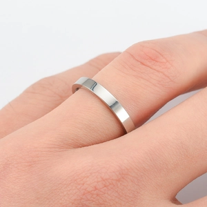 Close-up of minimalist 6mm silver polished stainless steel band ring worn on finger