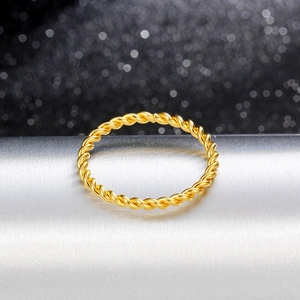 Close-up of a minimalist 18K gold twisted rope ring on a silver display stand
