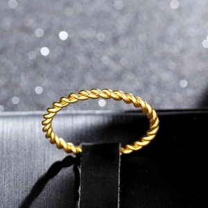 Macro shot of 18K rose gold twisted rope ring with elegant metallic texture on black leather