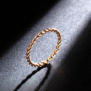 Detailed view of twist woven 18K rose gold ring with spiral texture on black background
