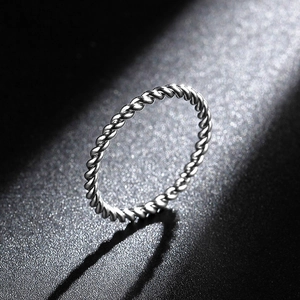 Macro shot of silver twisted rope texture ring with polished metallic finish on black background