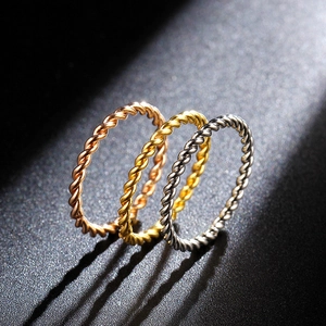 Detailed close-up of three twisted stackable rings in rose gold, gold, and silver finishes