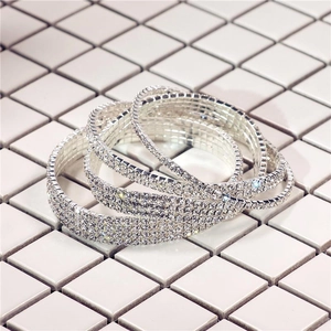 Détail des bracelets multicouches en strass argentés superposés sur carreaux blancs