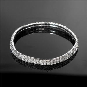Détail d'une chevillère double rangée avec strass blancs sur surface noire réfléchissante