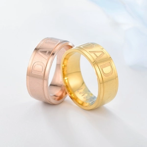 Makro-Detail von gebürsteten DAD-Ringen aus Titan mit Love-Gravur in Gold und Roségold