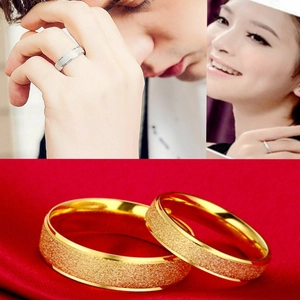 Close-up of gold frosted stainless steel couple rings with polished inner edges and red silk